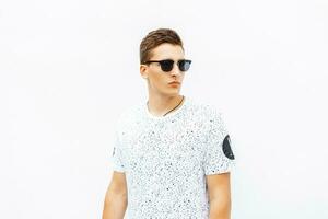 Stylish young man wearing sunglasses and hair standing on white background. photo