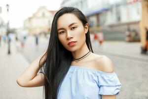 hermosa asiático mujer con largo pelo posando en un ciudad antecedentes. foto