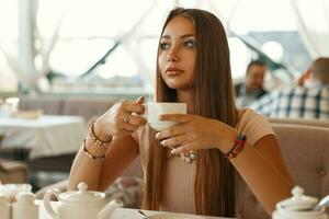 hermosa niña Bebiendo té en un verano cafetería. foto