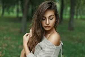 hermosa joven modelo niña con peinado en un de punto suéter en el parque foto