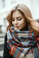 Cute young woman in trendy knitted scarf and black coat in autumn day photo