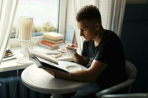 Handsome man drinking coffee and reads magazine in the cafeteria photo