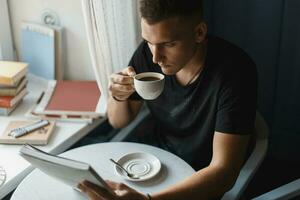 Young man reading a book and drinking coffee in a restaurant photo