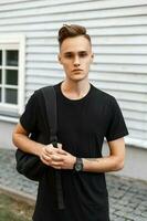 Handsome man with a backpack near a wooden house. photo