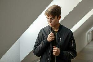 Handsome young man in a black fashion jacket posing near the window photo