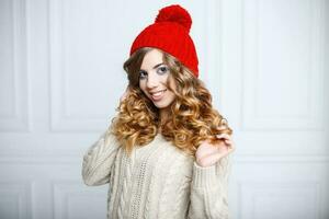 bonito mujer con un hermosa sonrisa en un rojo gorra y un de punto suéter foto