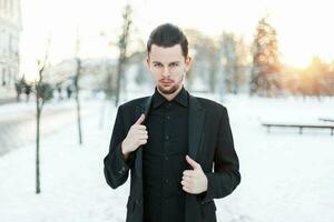 Handsome young man in a black suit at sunset photo