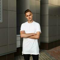 hermoso grave hombre en un blanco camiseta posando cerca el pared. foto