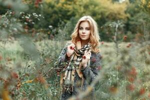 Beautiful young girl in a vintage scarf and coat near the tree with berries. Autumn day photo