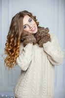 Beautiful cheerful girl with amazing smile in a warm sweater and mittens photo