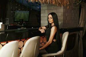 hermosa joven mujer en un negro vestir relajante en el bar. foto