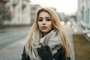 Portrait of a beautiful young blonde girl in autumn clothes on a background of the city. photo