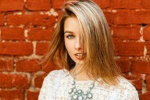 Portrait of a beautiful young girl near the red brick wall. photo