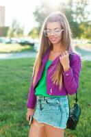 Beautiful stylish girl in a bright colorful fashionable clothes and sunglasses on a sunny day. photo