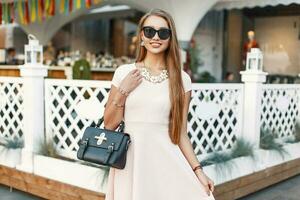 Cheerful young girl in a pink dress with handbag has fun photo