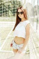 Sexy beautiful hipster woman in sunglasses standing near beach grid. photo