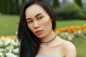 Beautiful portrait of a pretty asian woman on a background of spring flowers photo