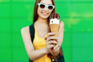 Beautiful cheerful girl smiling and holding an ice cream. Delicious ice cream cone closeup. photo