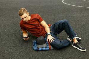 Modern handsome man uses the phone and lying on the pavement. photo