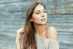 Sexy young beautiful woman in a vintage gray sweater near the blue wooden wall photo