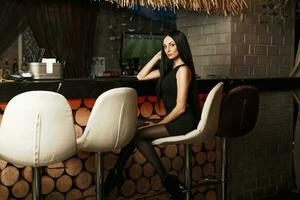 hermosa elegante mujer sentado en un silla y descansando a el bar. foto