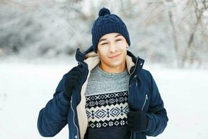 Young handsome man with a smile in winter clothes in a knitted sweater with a pattern posing in the park. photo