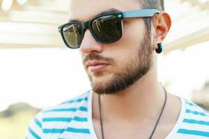 de cerca retrato de un joven hermoso hombre en Gafas de sol en un soleado día. foto