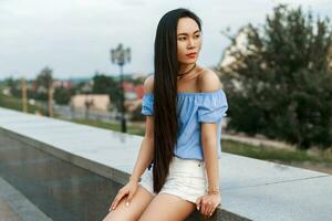 Beautiful girl with long black hair resting on a city background. photo