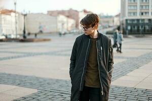 Young man in black jacket fashionable walks in the city photo