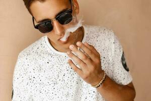 Young handsome guy smoking a cigarette. Clouds of smoke. photo
