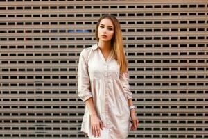 Stylish beautiful girl in fashionable clothes standing near a metal wall photo