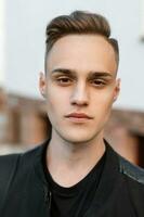 Close-up portrait of a young handsome man with the hairstyle. photo