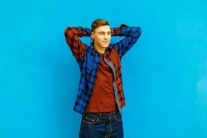 Handsome happy young man in fashionable jacket near a bright blue wall photo