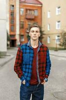 Handsome man in a checkered shirt on the background of buildings photo