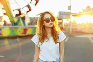 Portrait of a beautiful red-haired girl in sunglasses at sunset. photo