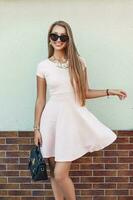 Funny beautiful girl in a pink dress near the wall photo