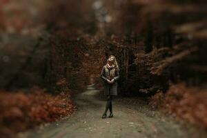 Young woman in coat and scarf walk in an amazing park photo