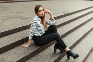 elegante hermosa mujer en de moda ropa sentado en el escaleras. foto