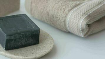 black color natural soap bar and a towel on white video