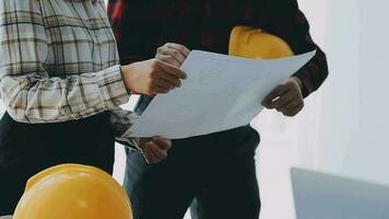 Image of engineering objects on workplace with three partners interacting on background video