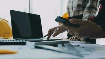 Image of engineering objects on workplace with three partners interacting on background video