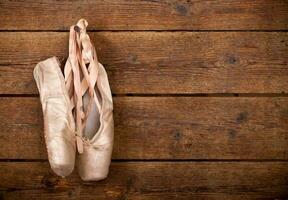 Old used pink ballet shoes hanging photo