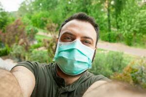 joven hombre haciendo un selfie con quirúrgico máscara durante el cuarentena período debido a el coronavirus COVID-19. foto