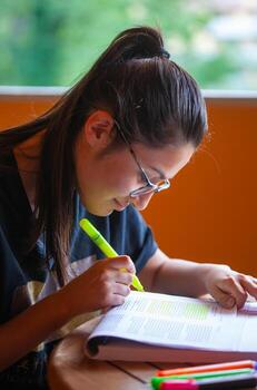 University student studying for an exam underlining text with highlighter. photo