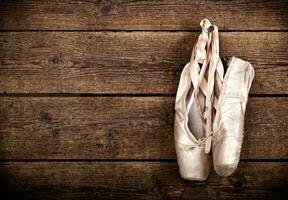 Old used pink ballet shoes hanging photo