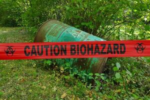 Caution biohazard tape barricading a rusty barrel photo