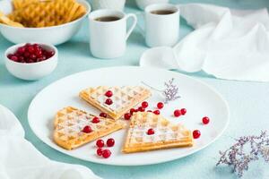 Heart shaped Belgian waffles with red berries and powdered sugar on a plate on the table. Valentine's Day photo