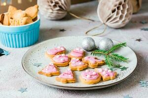Freshly baked Christmas cookies with pink icing on a plate on a decorated table. Festive treat. Close-up photo
