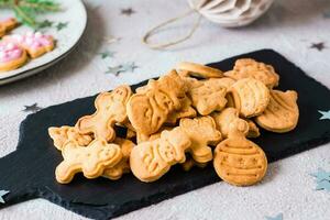 Freshly baked Christmas cookies are piled on a slate on a decorated table. Festive treat. Close-up photo