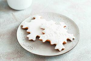 Gingerbread snowflakes with icing on a plate on the table. Christmas treat photo